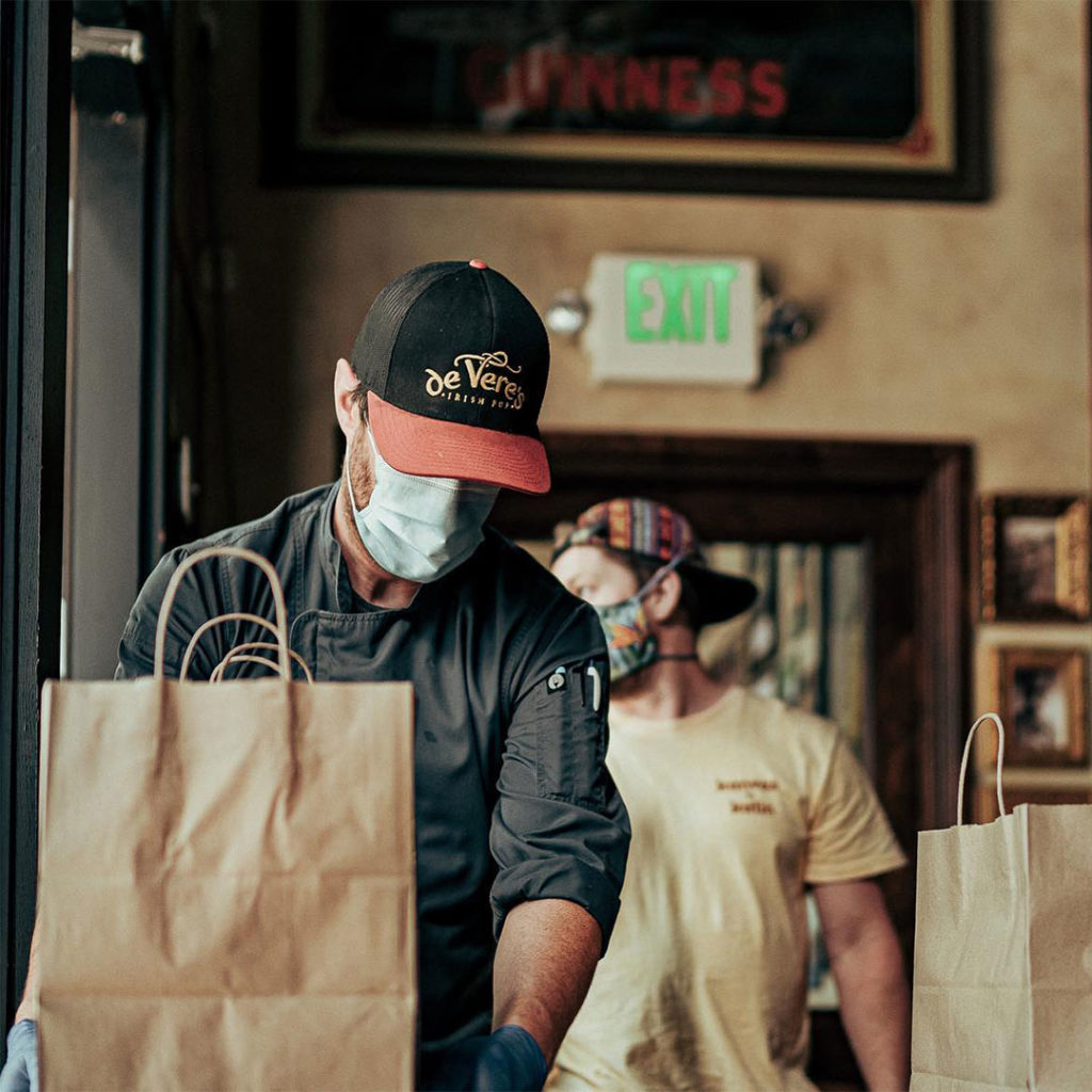 A restaurant worker is handling to-go orders in gloves and a mask to prevent the spread of Covid-19.