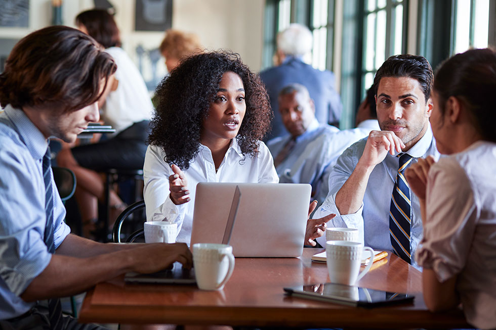 A business team is having an informal meeting around a table in a coffee shop.